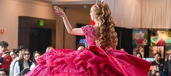 Quinceañera con vestido fucsia bailando frente al público